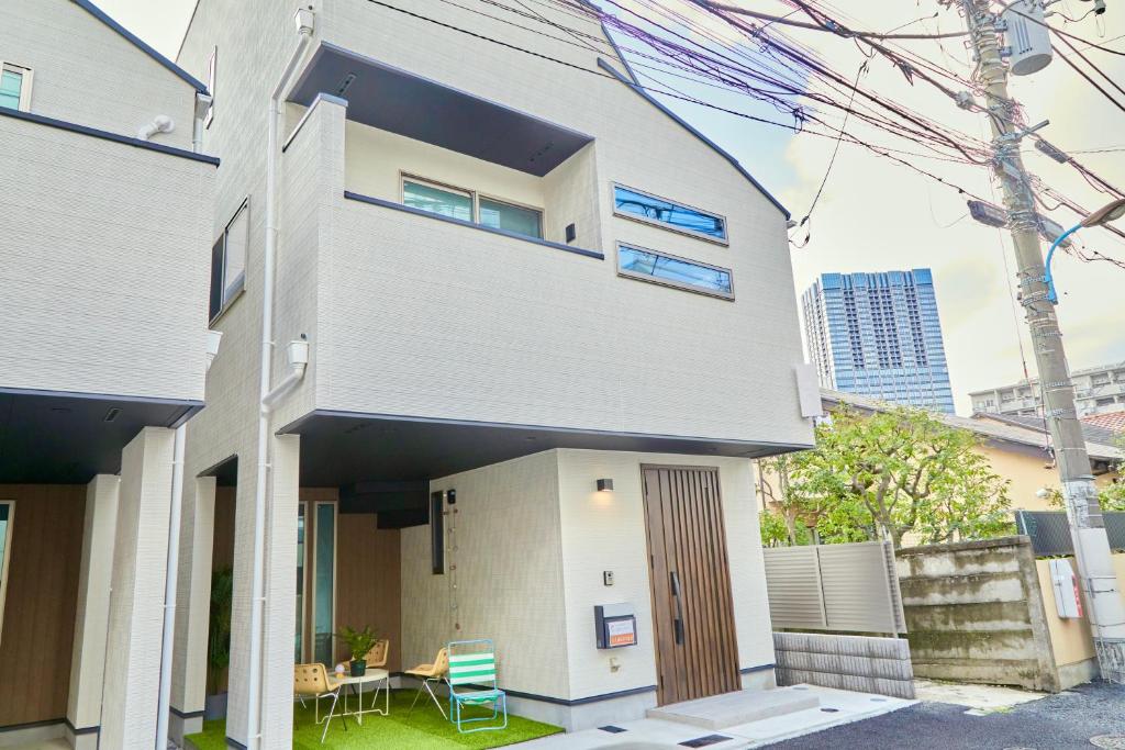 een wit huis met een tafel en stoelen ervoor bij Orange County in Shinjuku in Tokyo