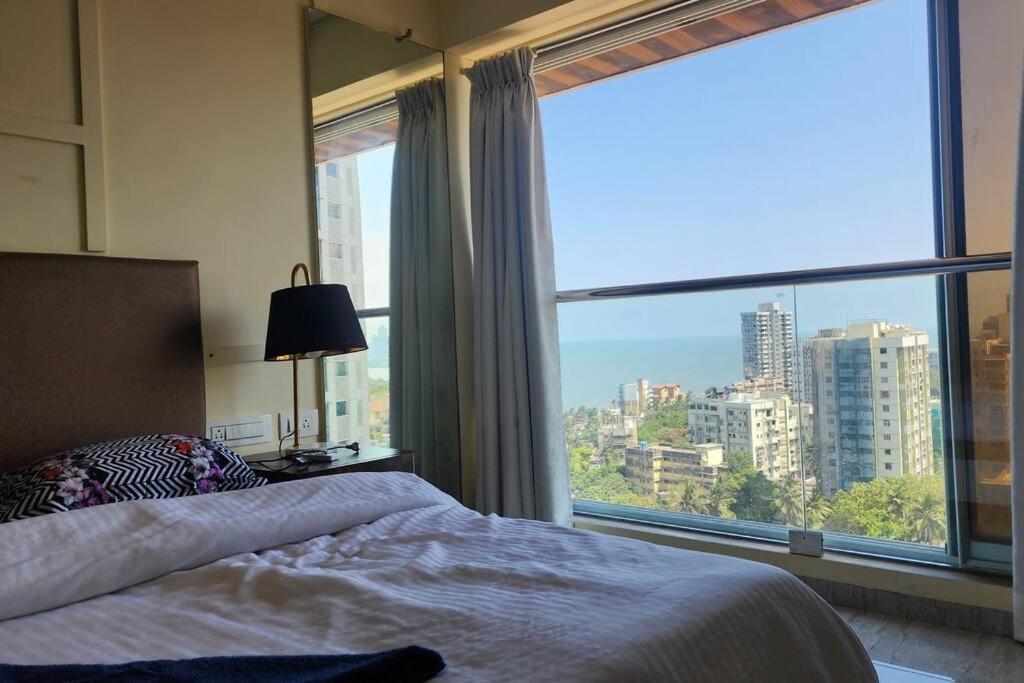 a bedroom with a bed and a large window at Ocean View Luxury Designer condo in Mumbai