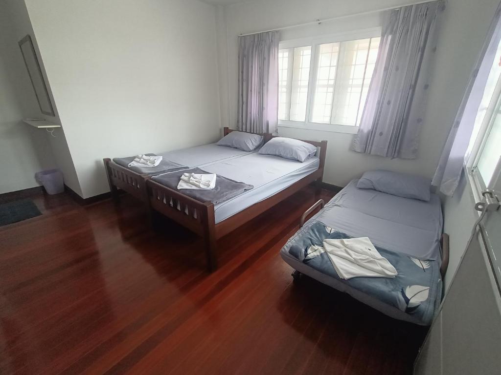 a room with two beds and a table and a window at Journey House Bangsean in Ban Laem Thaen