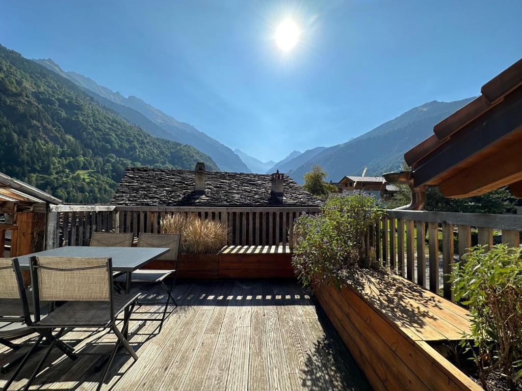 a wooden deck with a table and chairs and mountains at Le Nid - Versegere near Verbier - 4 Valleys in Versegeres 