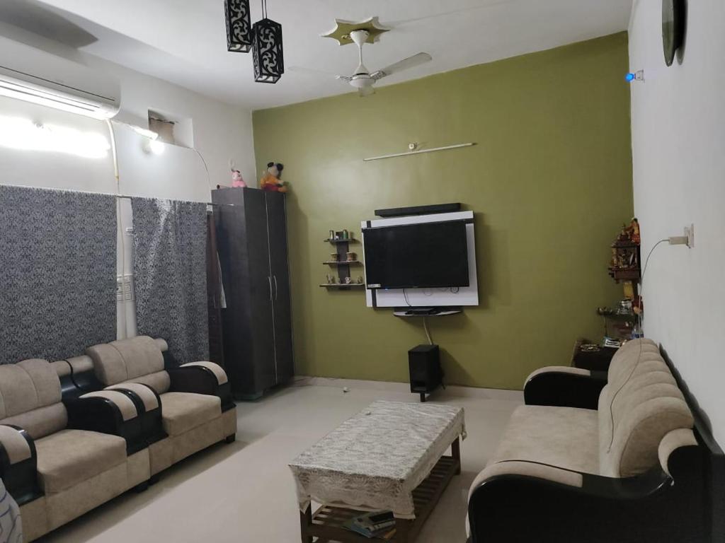 a living room with couches and a flat screen tv at Varanasi homestay in Varanasi