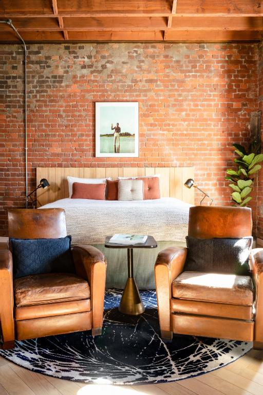ein Schlafzimmer mit einem Bett und zwei Stühlen in der Unterkunft Old Foundry Hotel by Ideas Cartel in Kapstadt