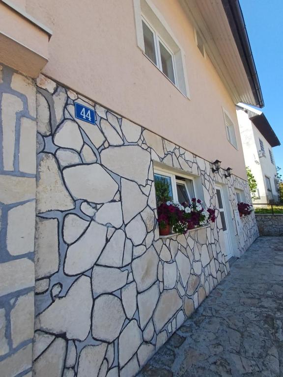 een stenen muur naast een gebouw met een raam bij Apartment Kalpačina in Žabljak