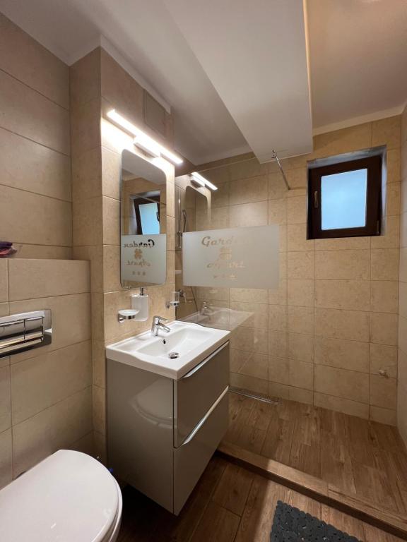 La salle de bains est pourvue d'un lavabo blanc et de toilettes. dans l'établissement Apartamente de inchiriat- Garden Apart Predeal, à Predeal