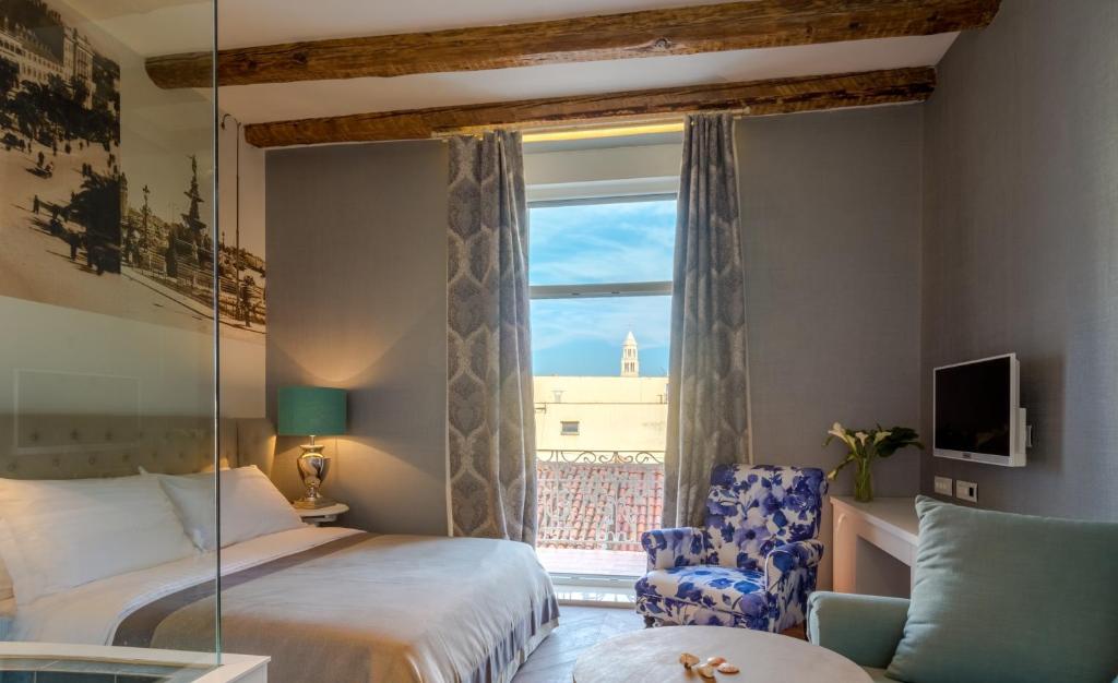 ein Schlafzimmer mit einem Bett, einem Fenster und einem Stuhl in der Unterkunft Procurator 7 Luxury Rooms in Split