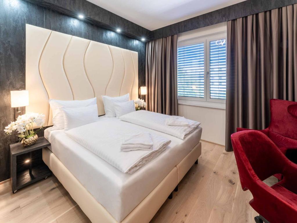 ein Schlafzimmer mit einem großen weißen Bett und einem roten Stuhl in der Unterkunft PLAZA INN Wiener Neustadt, BW Signature Collection in Wiener Neustadt