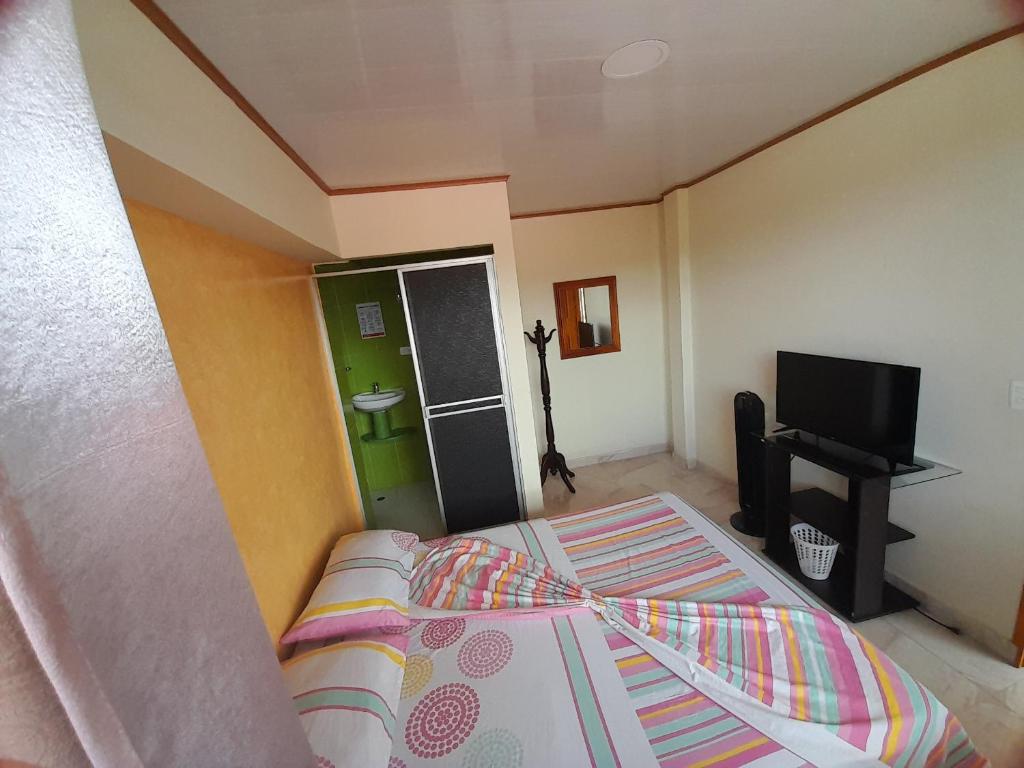 a bedroom with a bed and a flat screen tv at Alojamiento Panamericano San Miguel in El Bordo