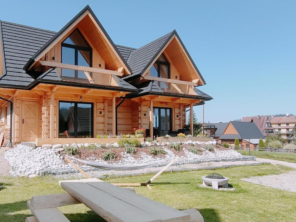 una casa de madera con un patio con un banco en Domki Hygge Tatra Luxury Chalet, en Murzasichle