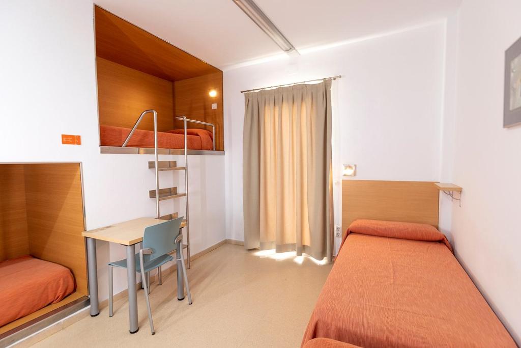 a bedroom with two beds and a desk and a table at Albergue Inturjoven Torremolinos in Torremolinos