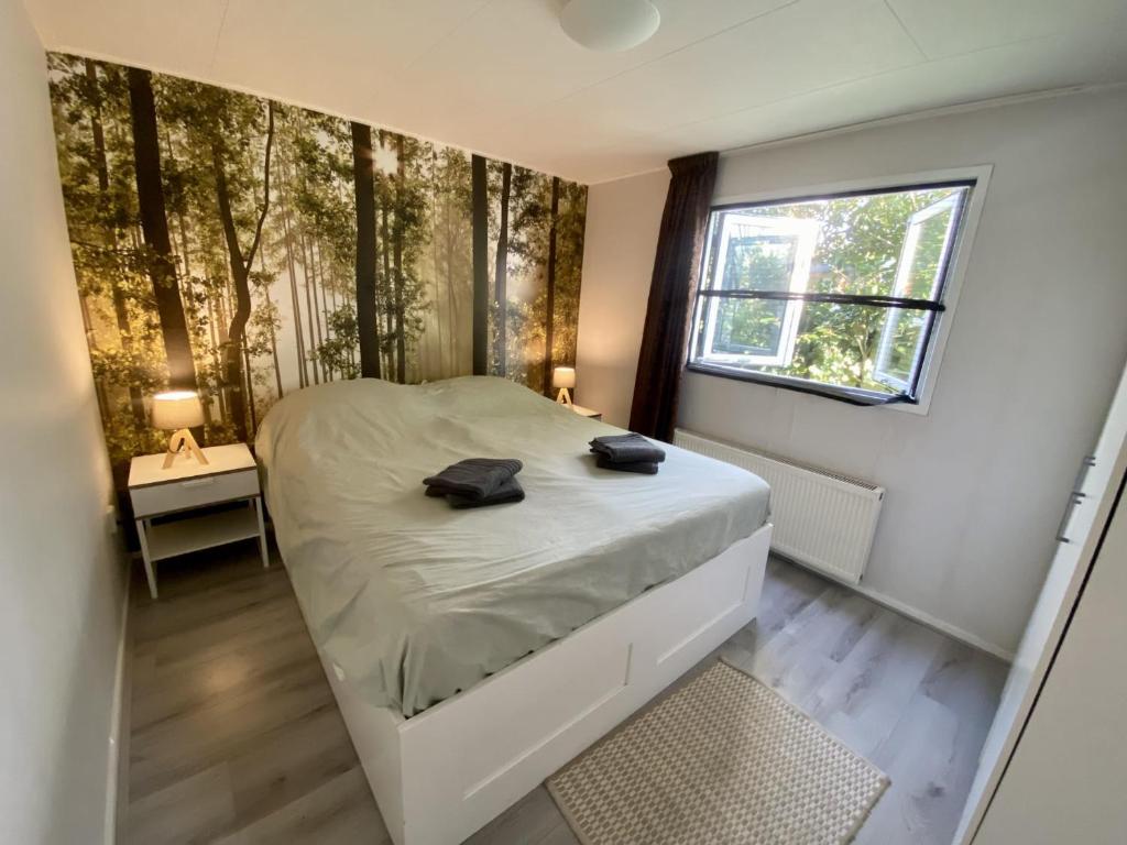 ein Schlafzimmer mit einem Bett in einem Zimmer mit Bäumen an der Wand in der Unterkunft VELUWE VAKANTIES Chalets With Private Barrel Sauna - With Pool Bar and Restaurant Facilities in the Veluwe National Park in Putten