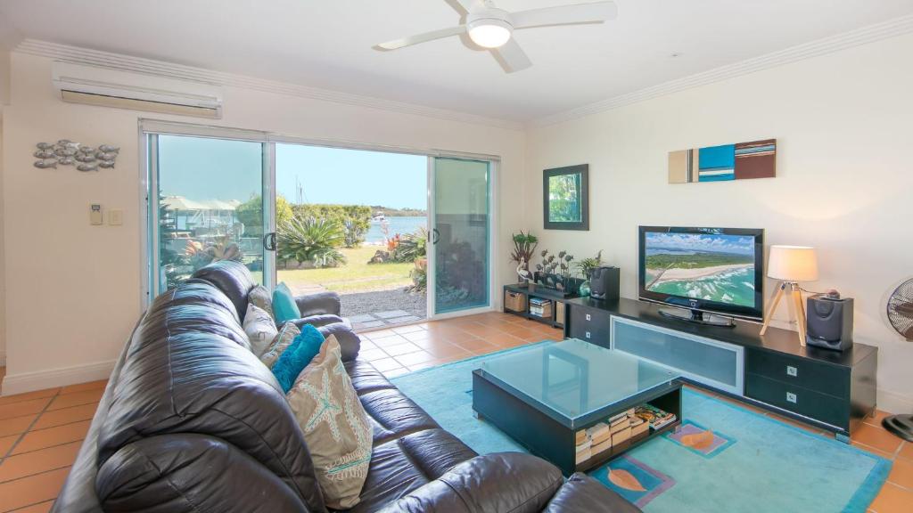 a living room with a leather couch and a television at Riverview Apartment 1 Block 1 in Iluka