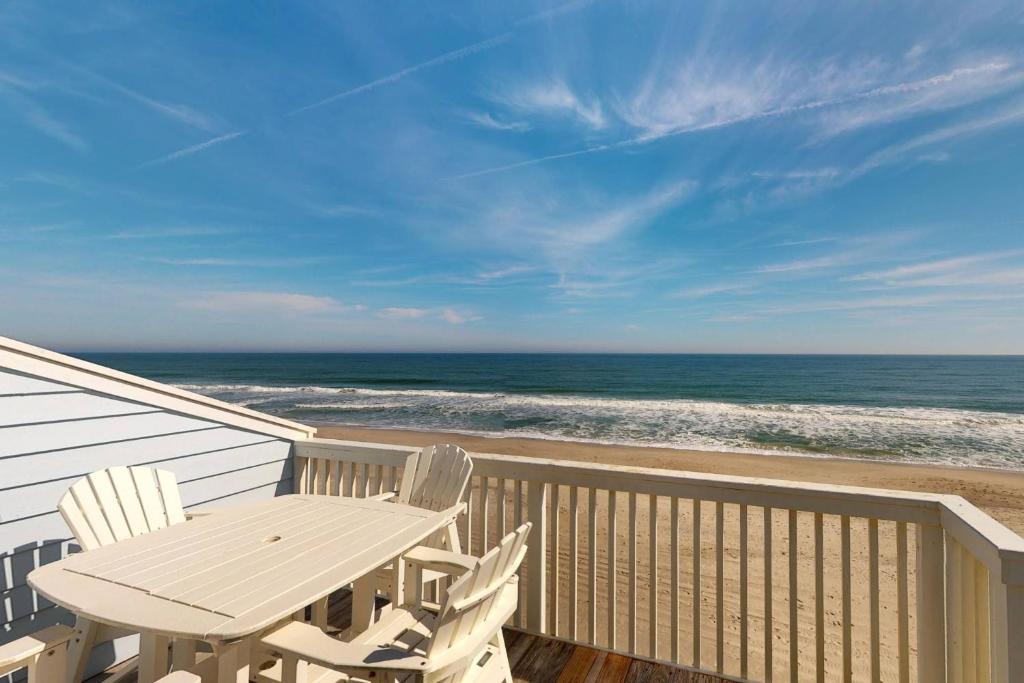 a table and chairs on a balcony with the beach at Saltwater Kure in Kure Beach