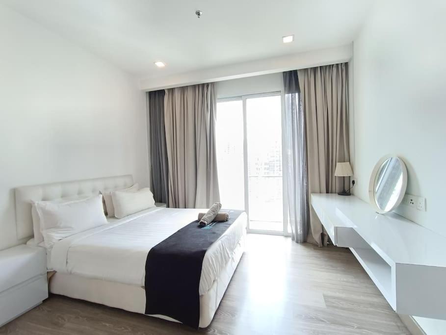 a white bedroom with a large bed and a mirror at RM2a18 Bukit Bintang Balcony Studio in Kuala Lumpur