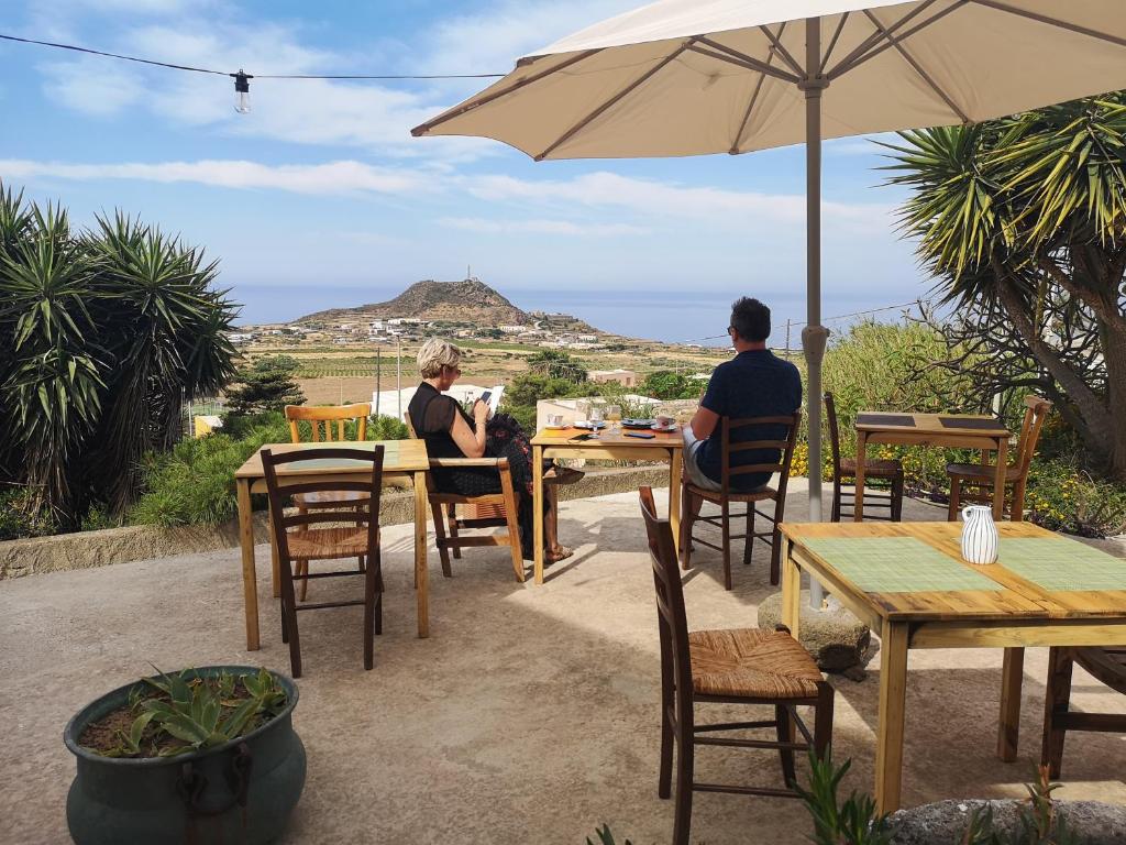 duas pessoas sentadas numa mesa com um guarda-chuva em Il Mulino di Scauri em Pantelleria