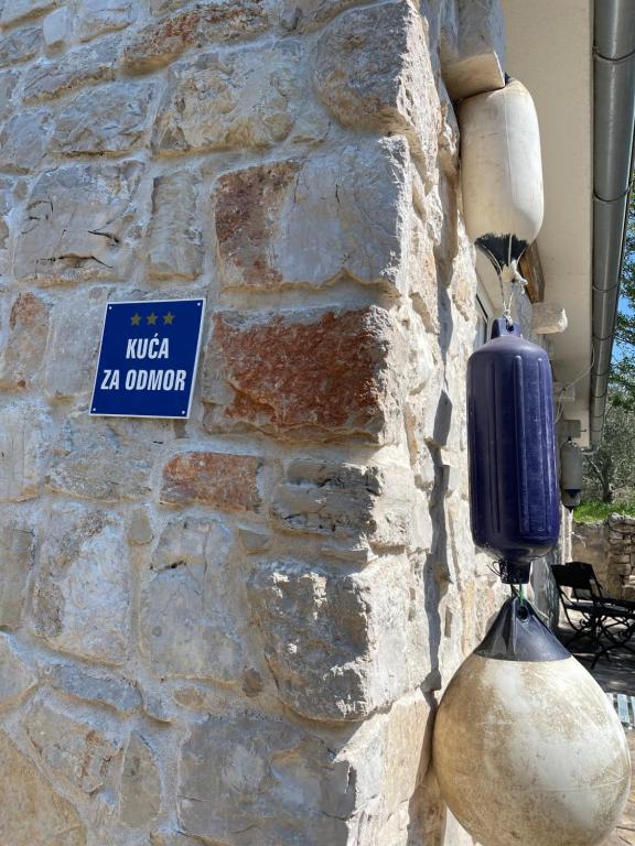 a stone wall with a blue and white sign on it at Kuća za odmor Ivančica in Tisno
