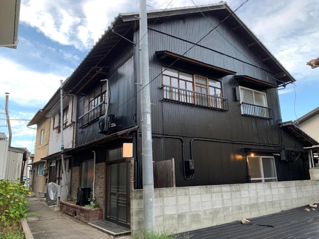 una casa negra con un poste delante en つばめ荘 Tsubamesou, en Onomichi