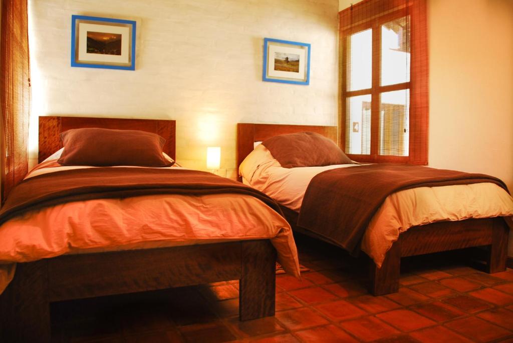 a bedroom with two beds and a window at Kutty Wasi in Cusco