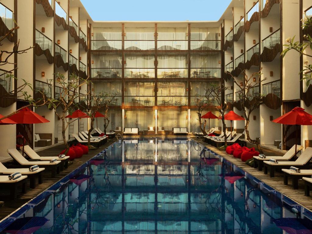 a large pool in a hotel with lounge chairs and a pool at The Bene Hotel in Kuta