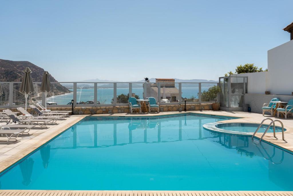 a pool with chairs and a view of the ocean at Areti Hotel in Agia Galini