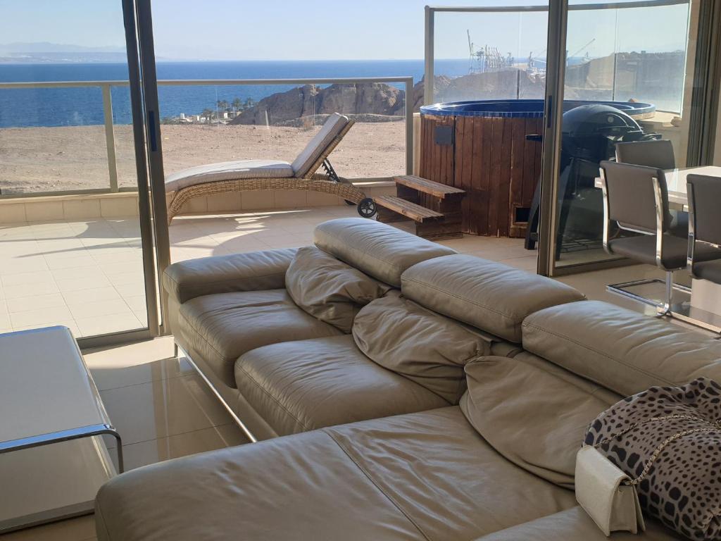 a living room with a couch and a view of the beach at Top-Luxury Exclusive Аpt with Jacuzzi in front of the sea in Eilat