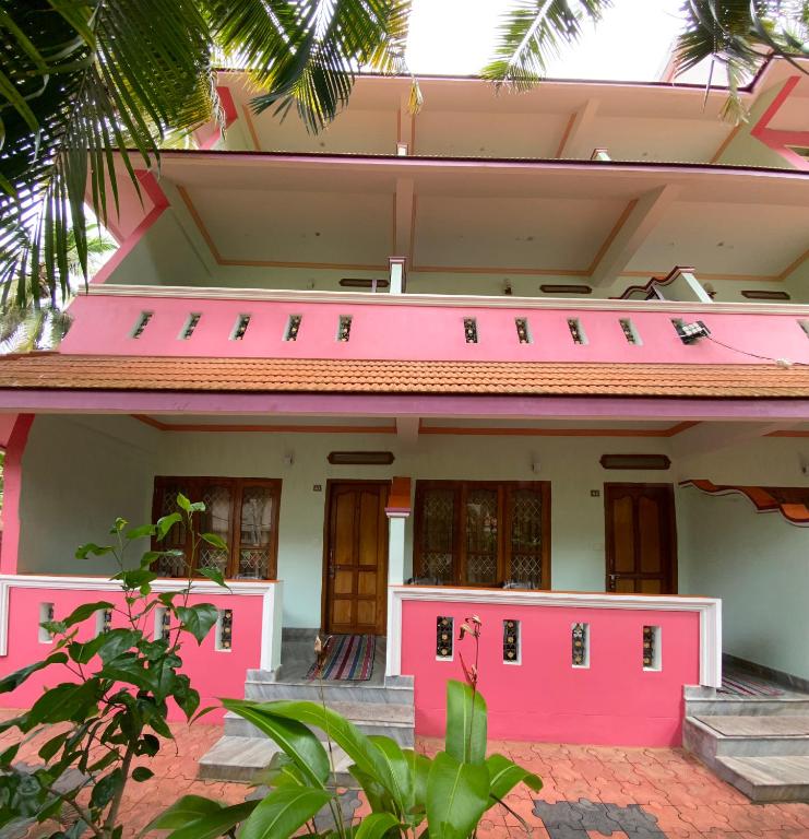 a pink house with stairs in front of it at Packbag Comfort Bed & Breakfast in Kovalam