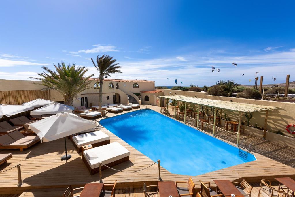 einen Pool auf einer Terrasse mit Stühlen und Sonnenschirmen in der Unterkunft Hotel Playa Sur Tenerife in El Médano