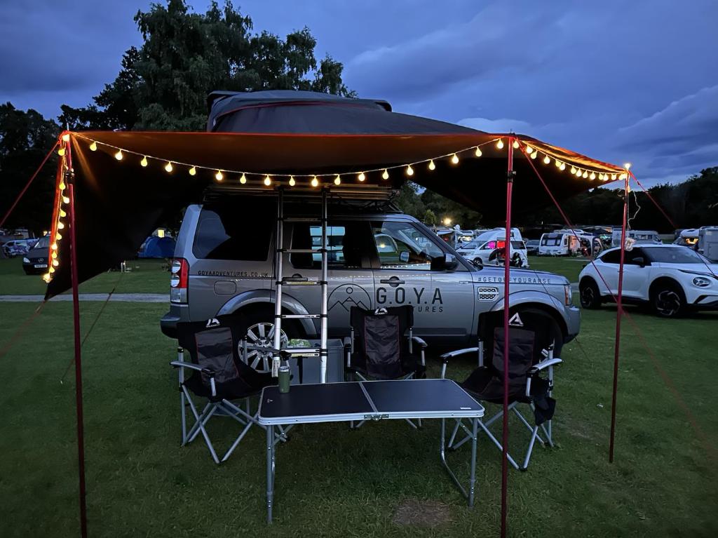 Discovery 4 - Family Camper في Inshes: شاحنة متوقفة تحت خيمة مع طاولة