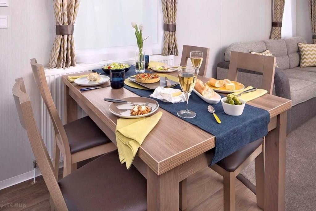 a dining room table with food and glasses of wine at Polladras Holiday Park in Helston