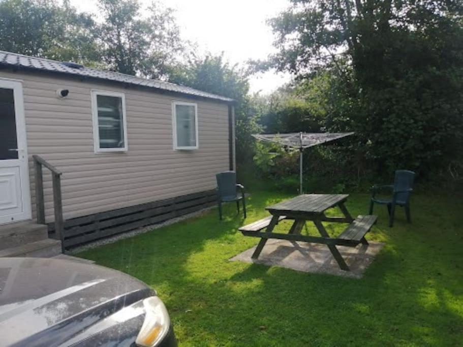 a picnic table and chairs in front of a house at Polladras Holiday Park in Helston