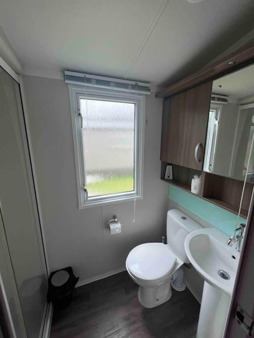 a bathroom with a toilet and a sink and a window at Polladras Holiday Park in Helston