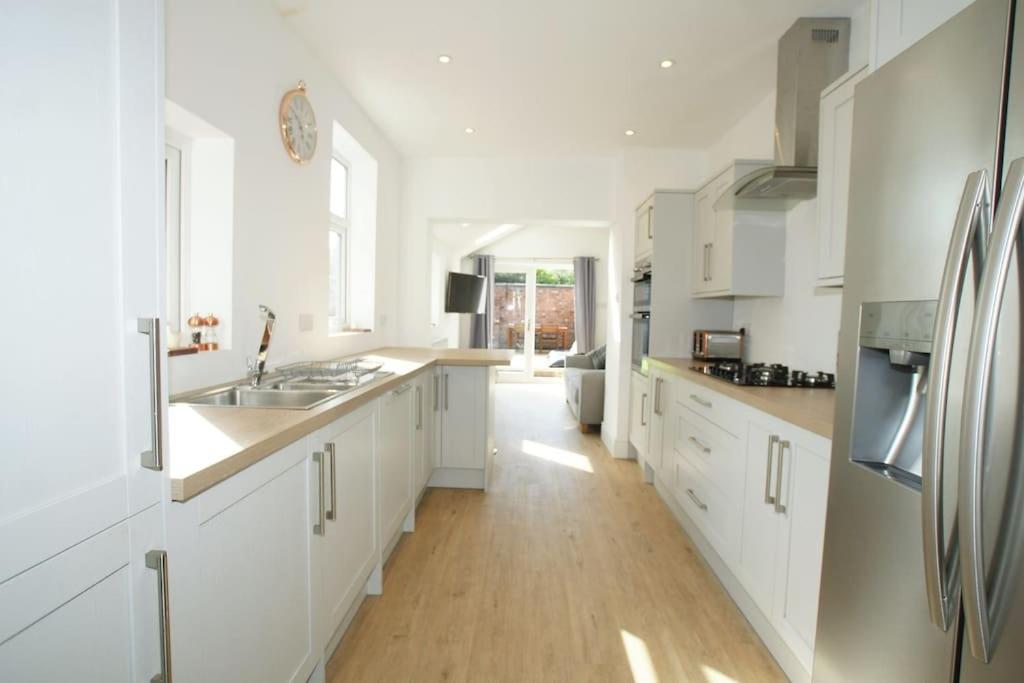 eine Küche mit weißen Schränken und Holzböden in der Unterkunft Modern 4 bed house near city centre/Chester Zoo in Chester