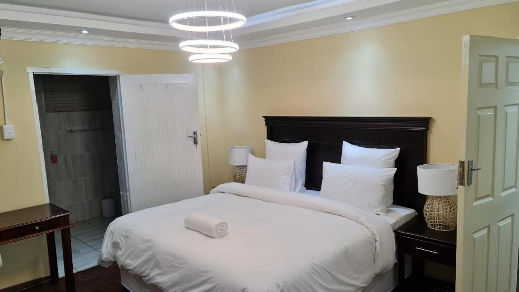 a bedroom with a large bed with white sheets and pillows at Suprime Hotels and Conference in Pietermaritzburg