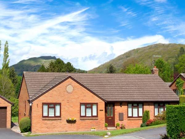 a brown brick house with mountains in the background at Tregarthens in Church Stretton