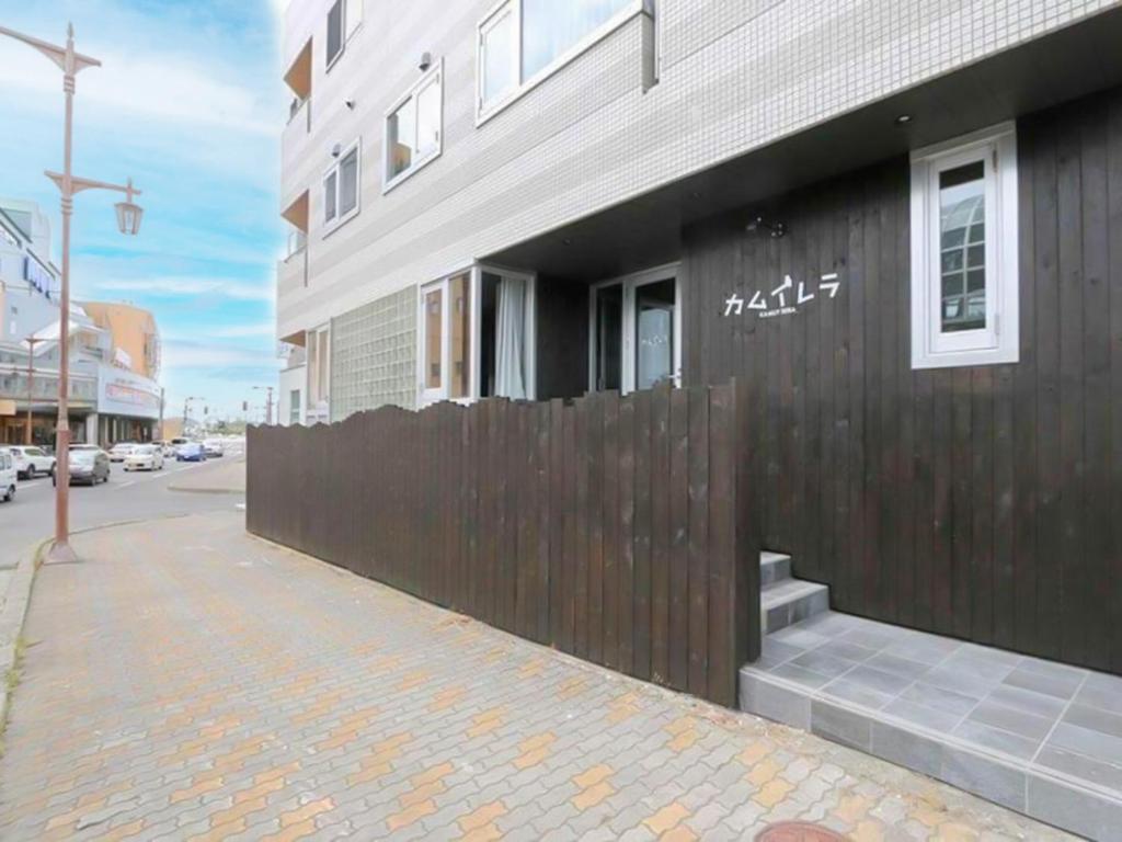 un bâtiment avec une clôture en bois à côté d'une rue dans l'établissement Kamuy Rera, à Kushiro