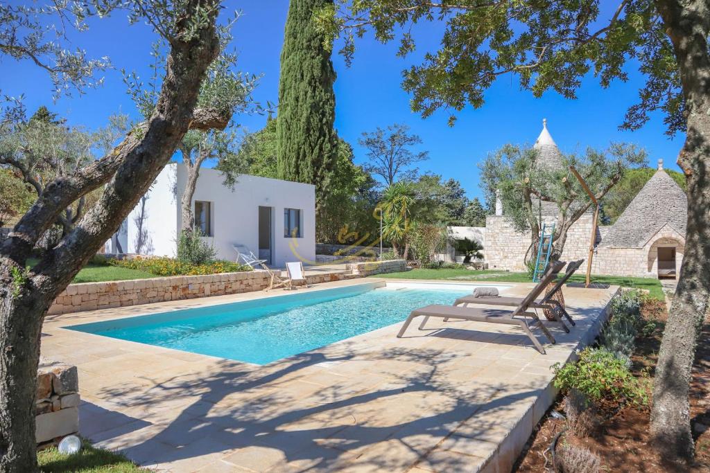 a swimming pool in a yard with trees and a house at TD Trulli Tortorella with Nature Pool Sauna in Monopoli