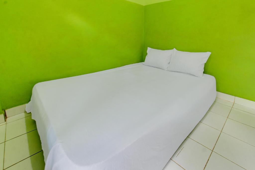 a large white bed in a green room at OYO Life 92829 Kos Insan Madani in Praya