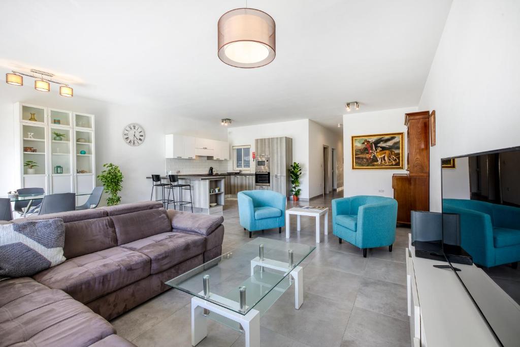 a living room with a couch and blue chairs at Annitchka Mansions - Apartment in central Malta in Birkirkara