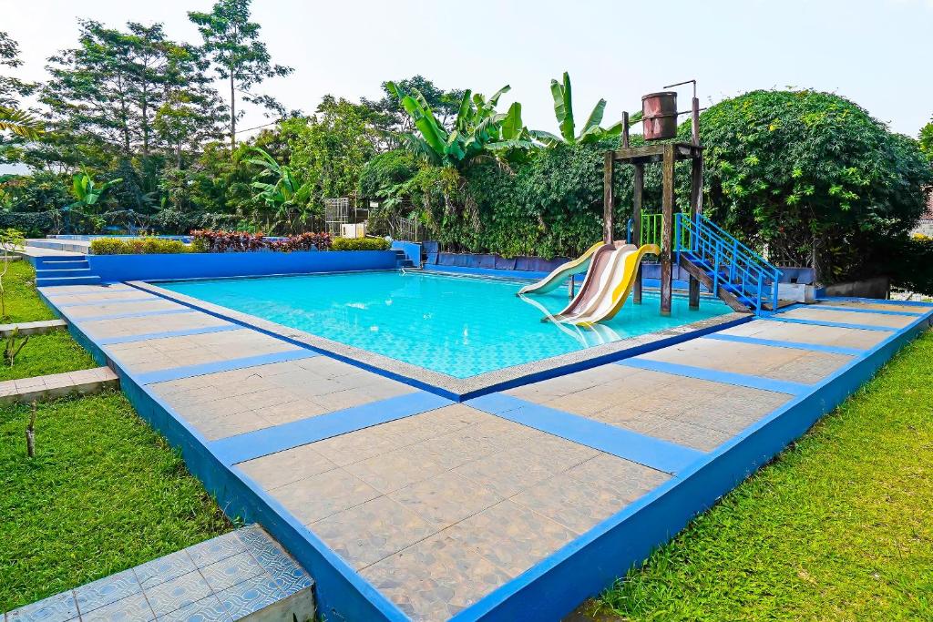 a swimming pool with a slide in the grass at OYO Life 92835 Maya Adipuri in Bandung