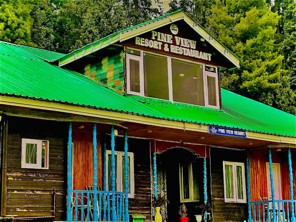 un bâtiment en bois avec un toit vert et un panneau dans l'établissement Pine View Resort, à Gulmarg