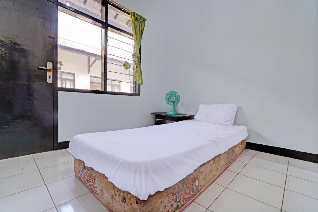 a bedroom with a white bed with a window at OYO Life 92901 Kost Bu Nur in Bandung