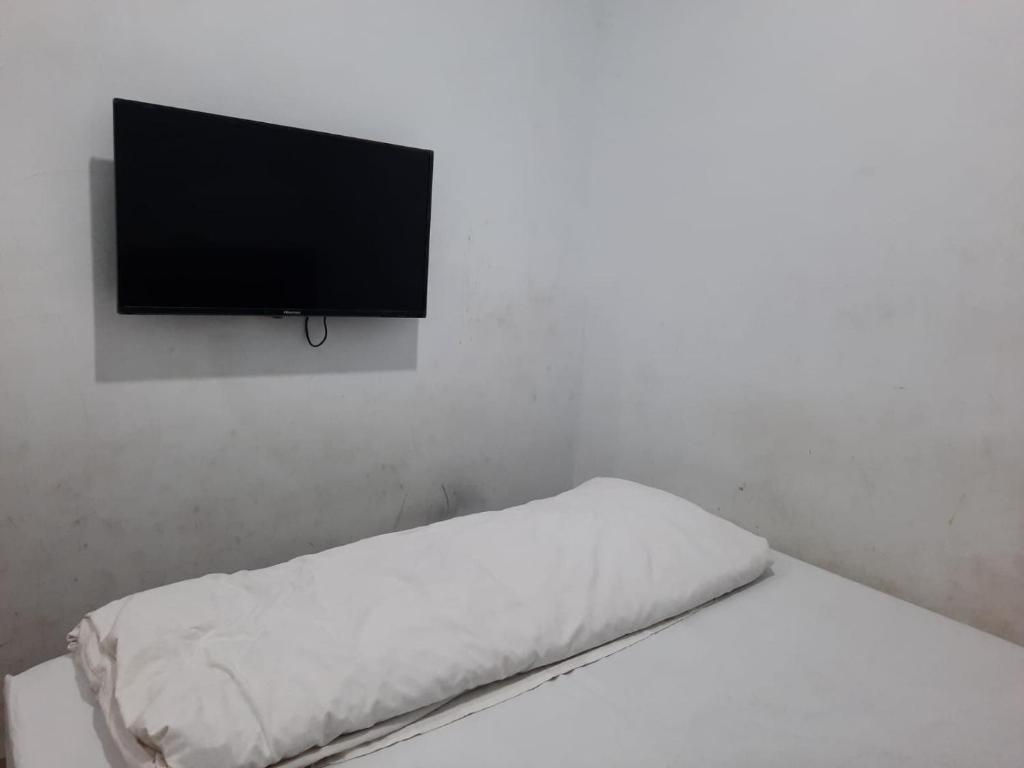 um quarto branco com uma cama e uma televisão de ecrã plano em OYO Life 92883 Kost Ratana Cengkareng Syariah em Jakarta