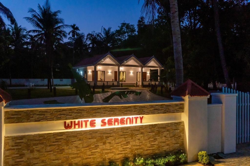 a white sanctuary sign in front of a house at night at White Serenity Villa Udupi in Udupi
