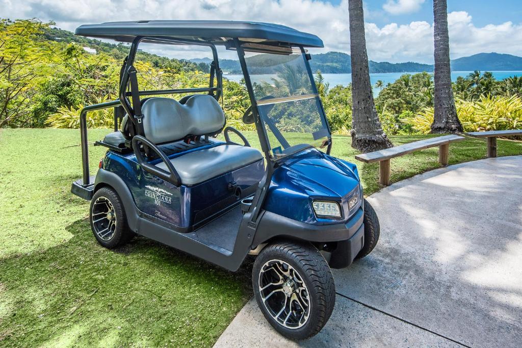 a blue golf cart parked on the grass at POINCIANA 101 HAMILTON ISLAND CENTRALLY LOCATED 3 BEDROOM, plus BUGGY!! in Hamilton Island