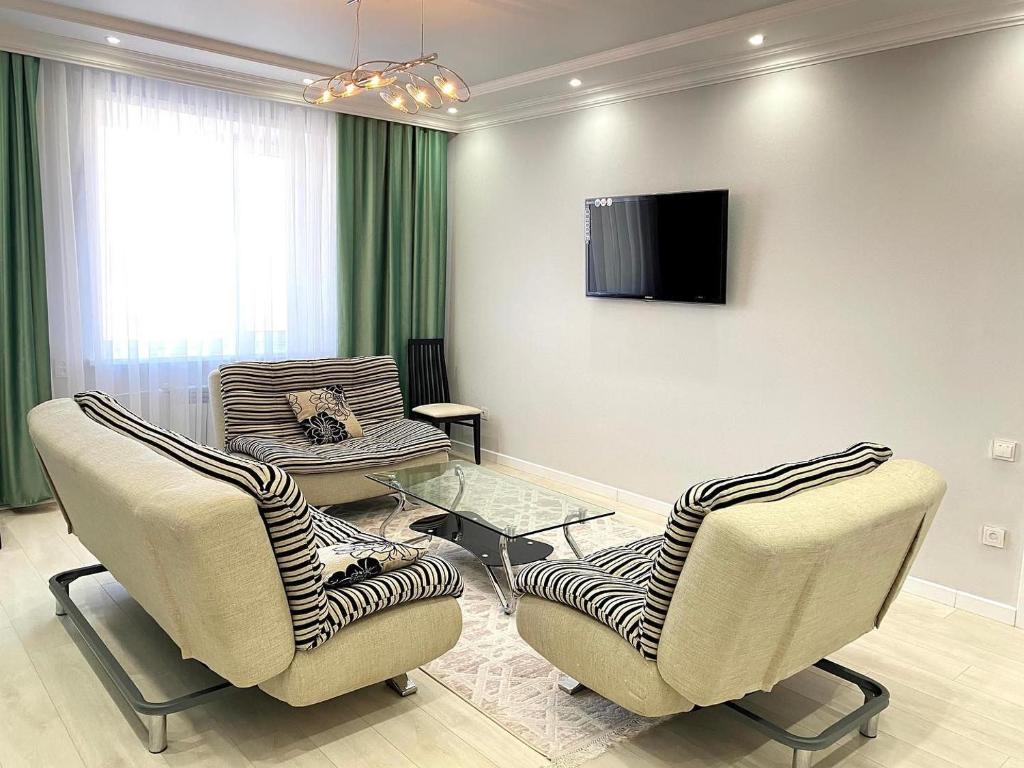 a living room with two chairs and a tv at Luxe Appartments on Stepnoy in Karagandy