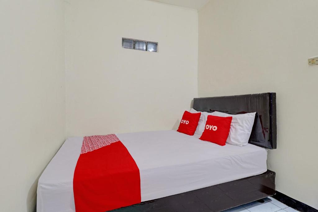 Una cama en una habitación con almohadas rojas. en OYO Life 92685 Kost Arimbi, en Bandung