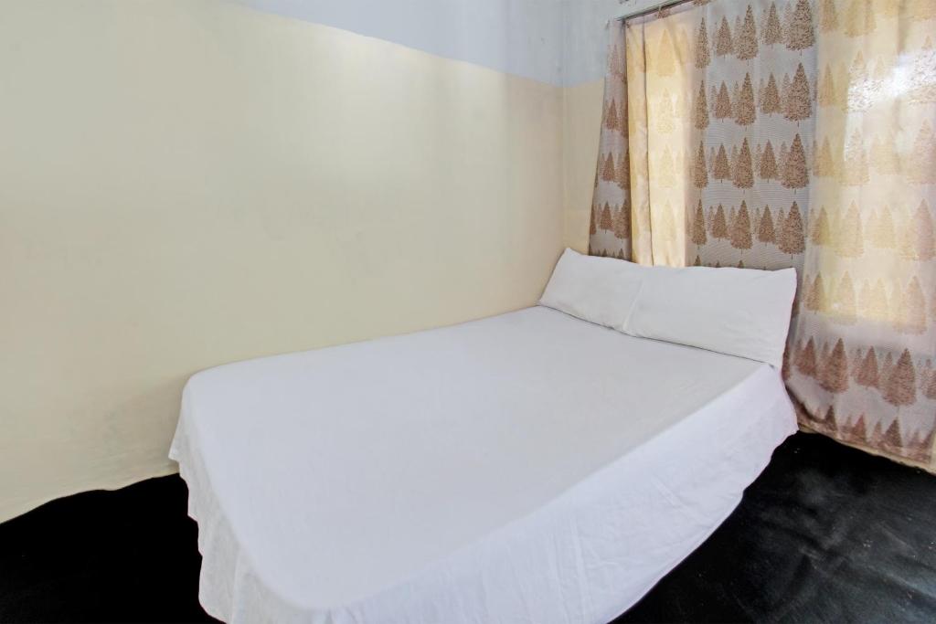 een wit bed in een kamer met een raam bij OYO Life 92853 Kost 999 in Lombok
