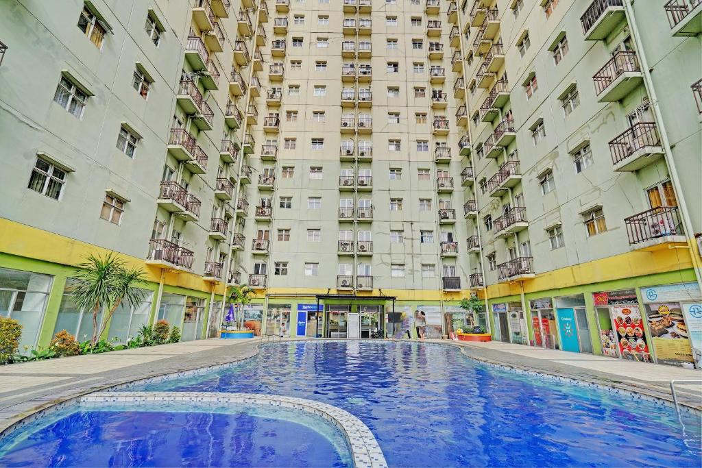 ein großes Gebäude mit einem Pool davor in der Unterkunft OYO Life 92984 The Suites Metro Apartement By Echie Property in Bandung