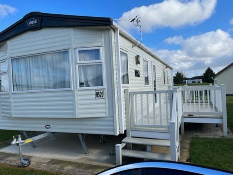 a white caravan with a porch and two chairs at 3 Bed 2 Bath Static Mobile Home On Fantastic Park in Mablethorpe