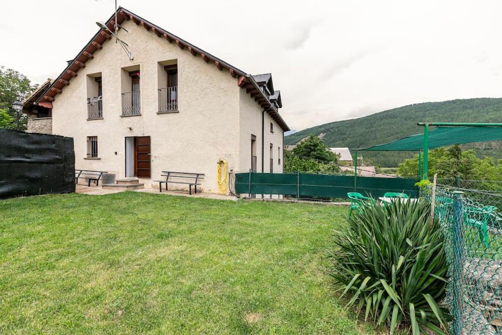 a house with a grass yard in front of a building at Casa Luis - APARTAMENTO con JARDÍN PRIVADO en los PIRINEOS in Castiello de Jaca