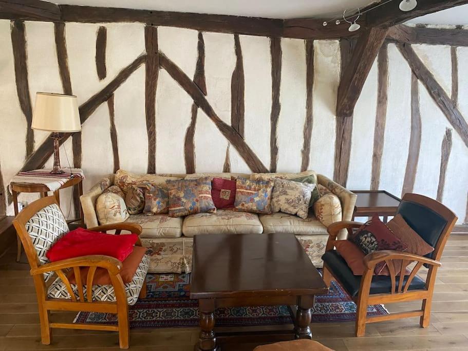uma sala de estar com um sofá, cadeiras e uma mesa em La maison familiale em Auxerre